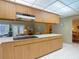 Bright kitchen featuring wood cabinets, a smooth cooktop, and a view into the adjacent living space at 10930 Marjory Ave, Tampa, FL 33612