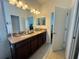 Dual sink bathroom vanity with granite countertops, tile floors, and access to bedroom at 12032 Grand Kempston Dr, Gibsonton, FL 33534