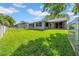 Wide backyard view with a lush lawn, fencing, and the back of the house at 12401 Yorktown Ln, Bayonet Point, FL 34667