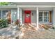 Covered front porch with brick walkway, red door, and wood trim details at 12401 Yorktown Ln, Bayonet Point, FL 34667