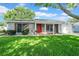 Charming single-story home featuring a well-manicured lawn, a bright red front door, and tasteful landscaping at 12401 Yorktown Ln, Bayonet Point, FL 34667