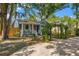 Charming blue home with a covered front porch, lush landscaping, and an inviting pergola in the front yard at 1302 E Flora St, Tampa, FL 33604