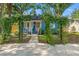 Charming blue home with a vine-covered pergola, leading to a delightful front porch and landscaped garden at 1302 E Flora St, Tampa, FL 33604