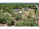 Wide aerial shot of a property with home, outbuildings, vehicles, and lush tree coverage at 13341 Hexam Rd, Weeki Wachee, FL 34613