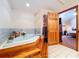 Bathroom featuring blue bathtub, tile floors, and a wood door to the bedroom at 13341 Hexam Rd, Weeki Wachee, FL 34613