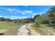 Exterior of the home with a long driveway, front porch, treed front yard, and various small outbuildings at 13341 Hexam Rd, Weeki Wachee, FL 34613