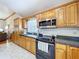 Well-lit kitchen featuring wood cabinets, black appliances, and granite countertops at 13341 Hexam Rd, Weeki Wachee, FL 34613