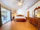Cozy main bedroom featuring wood floors, a ceiling fan, private patio access, and a charming dresser at 13341 Hexam Rd, Weeki Wachee, FL 34613