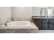 Bright bathroom features a soaking tub with tile surround and dark cabinetry at 1396 White Fox Run, Lutz, FL 33549