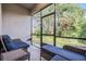 Relaxing screened patio featuring wicker furniture with comfortable blue cushions overlooking a lush backyard at 1396 White Fox Run, Lutz, FL 33549