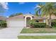 Charming single-story home boasts a well-manicured lawn, a two-car garage, and lush tropical landscaping at 14612 Corkwood Dr, Tampa, FL 33626