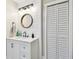 Bathroom features a white vanity, a round mirror, shiplap accent wall, and louvered door closet at 1529 Essex N Dr, St Petersburg, FL 33710