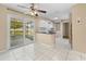 Open-concept kitchen features white cabinets, black countertops, tile floors and sliding glass doors to screened in patio at 1569 Larkin Rd, Spring Hill, FL 34608