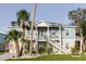 Charming two-story coastal home with a light blue exterior, complemented by palm trees and a well-manicured lawn at 216 High St, Tarpon Springs, FL 34689