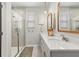 Bright bathroom featuring a double vanity with quartz countertops, gold-framed mirrors and a glass-enclosed shower at 2401 Morninglight Dr, Lutz, FL 33558