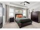 Well-lit bedroom with a dark wood bed frame, neutral walls, and a tray ceiling with fan at 2401 Morninglight Dr, Lutz, FL 33558
