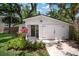 Charming white cottage with a covered entryway, black door, and a well-manicured garden with colorful plants at 3011 Harbor View, Tampa, FL 33611