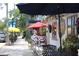 Inviting outdoor seating area with colorful umbrellas and lush greenery, along a quaint sidewalk at 3205 Coventry N, Safety Harbor, FL 34695
