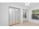 Bedroom featuring light colored laminate flooring, mirrored closet doors, and a window to the outside at 3447 Killdeer Pl, Palm Harbor, FL 34685