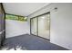 An outdoor patio with gray carpet, a sliding glass door, and a white privacy wall at 3447 Killdeer Pl, Palm Harbor, FL 34685