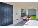 A cozy front porch area featuring a navy blue front door, red chairs, and a charming small table at 3739 Capri Coast Dr, Plant City, FL 33565