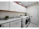 Well-lit laundry room with white cabinetry, granite countertops, and modern washer and dryer appliances at 3809 W San Pedro St, Tampa, FL 33629