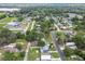 Aerial view of homes and streets surrounded by trees with green fields and a commercial building visible at 4802 18Th St, Zephyrhills, FL 33542