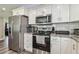Well-lit kitchen featuring stainless steel appliances, white cabinets and gorgeous granite countertops at 4802 18Th St, Zephyrhills, FL 33542