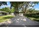 Single-story home featuring black and white exterior paint, brick accents, large driveway, and mature shade trees at 5405 S Sellas St, Tampa, FL 33611