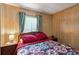 Bedroom featuring wood paneling, window, and bed with a colorful geometric patterned quilt at 5409 Antigua Dr, Zephyrhills, FL 33541
