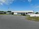 The community building has ample parking, an American flag, and pretty landscaping at 5409 Antigua Dr, Zephyrhills, FL 33541