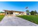 Charming home with a driveway, golf cart, chairs on the porch, and manicured lawn at 5409 Antigua Dr, Zephyrhills, FL 33541