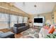 Comfortable living room features wood-paneled walls, plush seating, and abundant natural light from large windows at 5409 Antigua Dr, Zephyrhills, FL 33541
