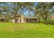 View of the house from the backyard, surrounded by mature trees and a well-maintained lawn at 56 Bay Woods Dr, Safety Harbor, FL 34695