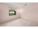 Unfurnished bedroom featuring medium-tone carpet, light pink walls, and a light fixture at 56 Bay Woods Dr, Safety Harbor, FL 34695