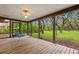 Screened porch featuring wood flooring, a swing, and views of the lush, green backyard at 56 Bay Woods Dr, Safety Harbor, FL 34695