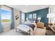 Bright bedroom with blue accent wall, stylish decor, and large windows offering scenic views of the outdoors at 727 Steel Dr, Apollo Beach, FL 33572