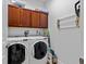 Functional laundry room with front-load washer and dryer and dark wood cabinets at 7309 S Shamrock Rd, Tampa, FL 33616