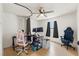 Bright bedroom features a ceiling fan, hardwood floors, two monitors, and a window allowing for natural light at 8010 Chickasaw Ln, Port Richey, FL 34668