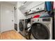 Laundry room with side-by-side washer and dryer on light wood floors and shelving for organized storage at 8010 Chickasaw Ln, Port Richey, FL 34668