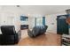 Open living room with wood floors, a ceiling fan, a fireplace, a dark entry door, and a comfortable seating area at 8010 Chickasaw Ln, Port Richey, FL 34668