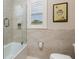 Clean bathroom with neutral tiles, a glass-enclosed shower, and a window with shutters for natural light at 852 Cordova Ne Blvd, St Petersburg, FL 33704