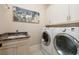 Bright laundry room with modern washer and dryer, a sink, and upper cabinet storage at 852 Cordova Ne Blvd, St Petersburg, FL 33704