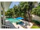 Beautiful backyard pool area with lush tropical landscaping, lounge chairs, and a bright blue umbrella at 852 Cordova Ne Blvd, St Petersburg, FL 33704
