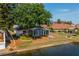 Charming waterfront home featuring screen enclosed porch, mature trees and lush lawn on a sunny day at 913 El Rancho Dr, Sun City Center, FL 33573