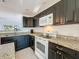 Close up of kitchen with granite countertops, dark cabinets, and white appliances at 9201 Tudor Dr # C212, Tampa, FL 33615