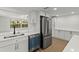 Well lit kitchen featuring stainless steel refrigerator, white cabinetry and modern appliances at 9241 Cochise Ln, Port Richey, FL 34668