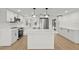Modern kitchen with white cabinets, stainless steel appliances, a center island, and hardwood floors at 9241 Cochise Ln, Port Richey, FL 34668