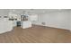 Open living space with light colored hardwood floors adjacent to a kitchen with an island and stainless appliances at 9241 Cochise Ln, Port Richey, FL 34668