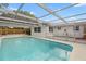 Lush backyard featuring a screened-in pool area, perfect for outdoor recreation and relaxation at 9241 Cochise Ln, Port Richey, FL 34668